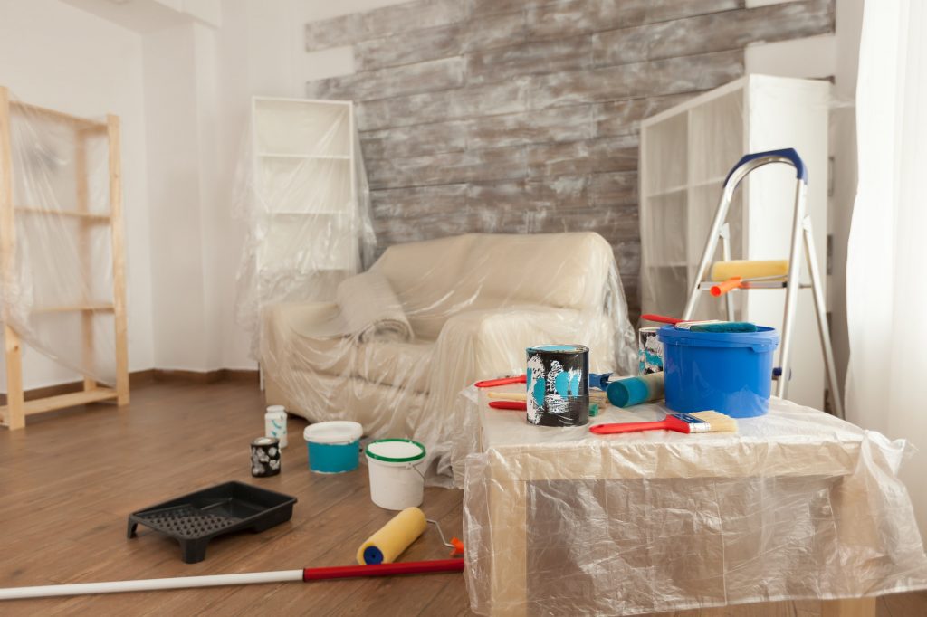 Værelse der har afdækningspap og plastik på gulve og møbler så værelset er klar til at blive malet